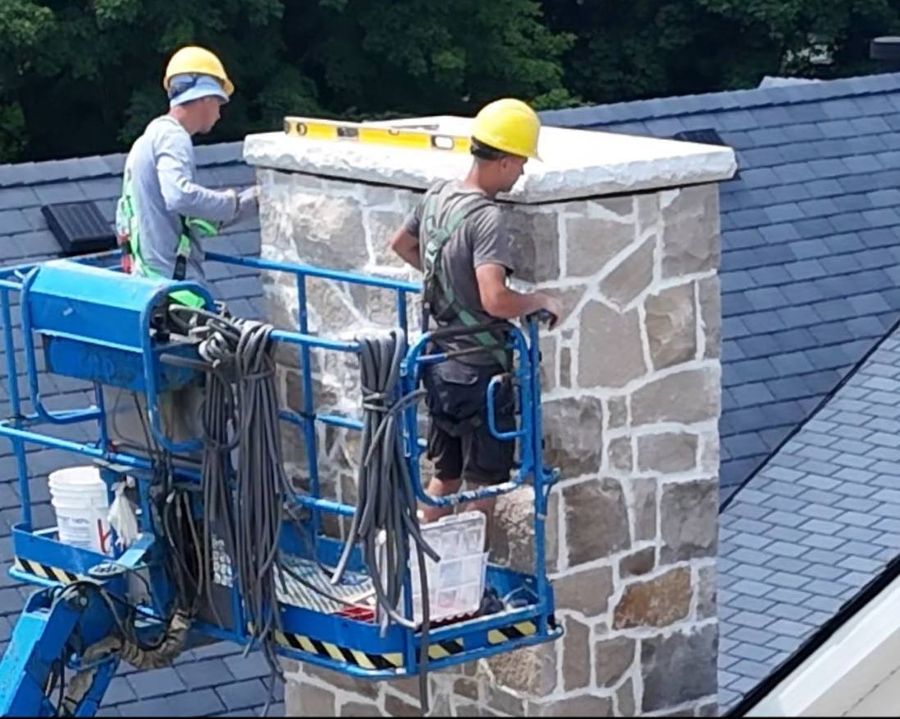 BBS Masonry crew installing a stone chimney cap from a lift