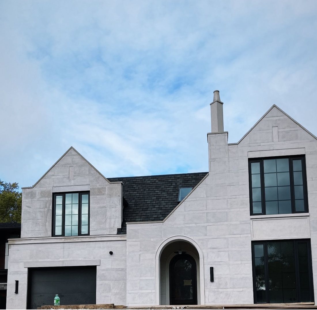 The Transitional Tudor Revival, a custom limestone home with a double entry arch and a solid limestone chimney flue
